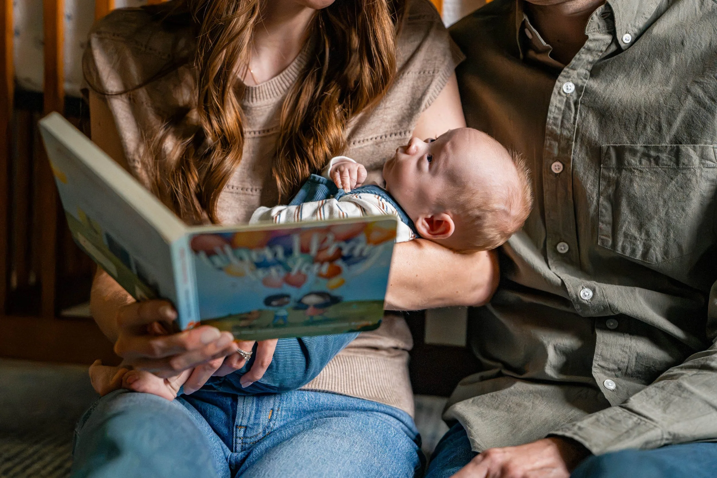 Baby boy in mom's arms while she reads the book When I Pray For You to him