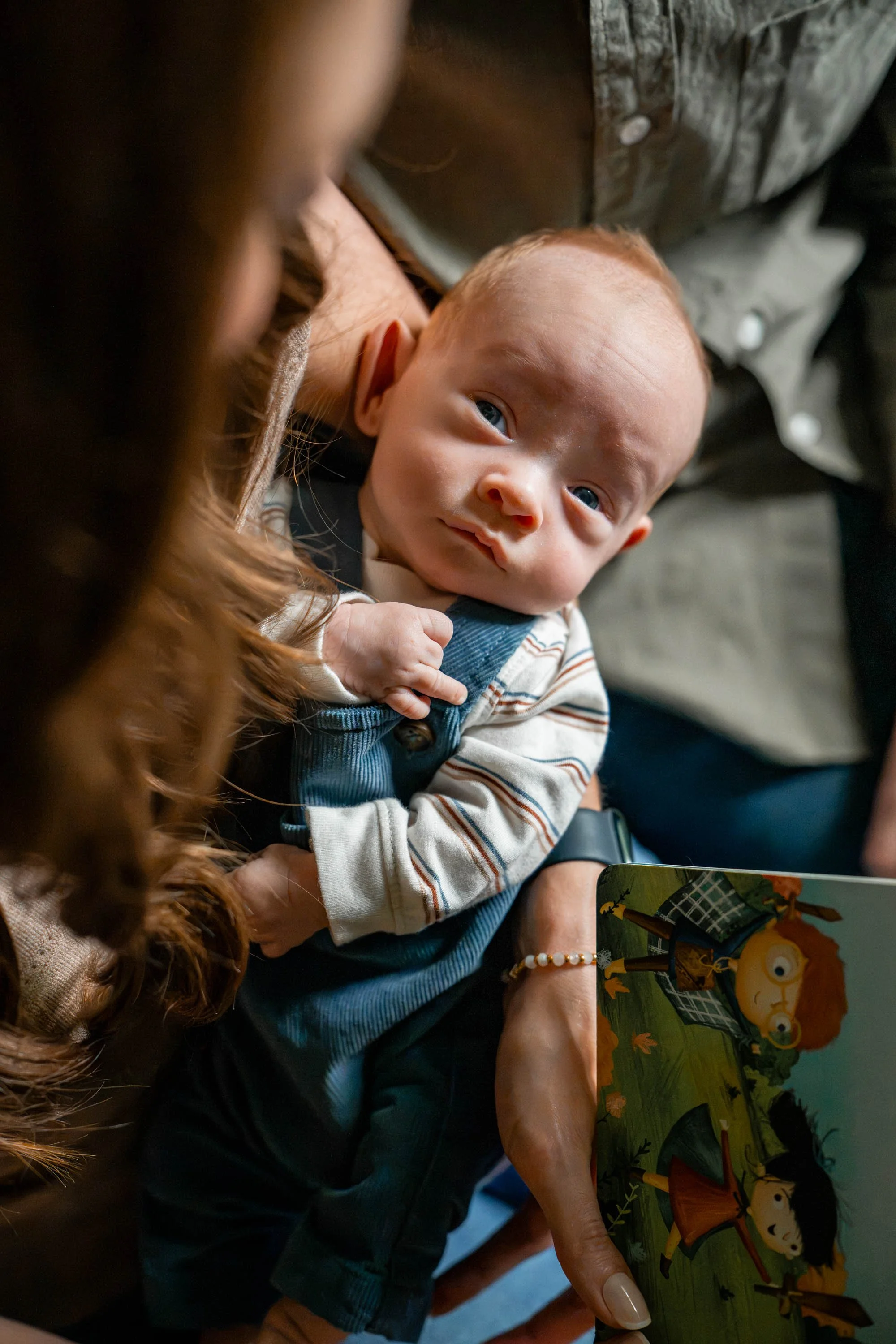 Baby looking up into the camera while snuggled in mom's arms