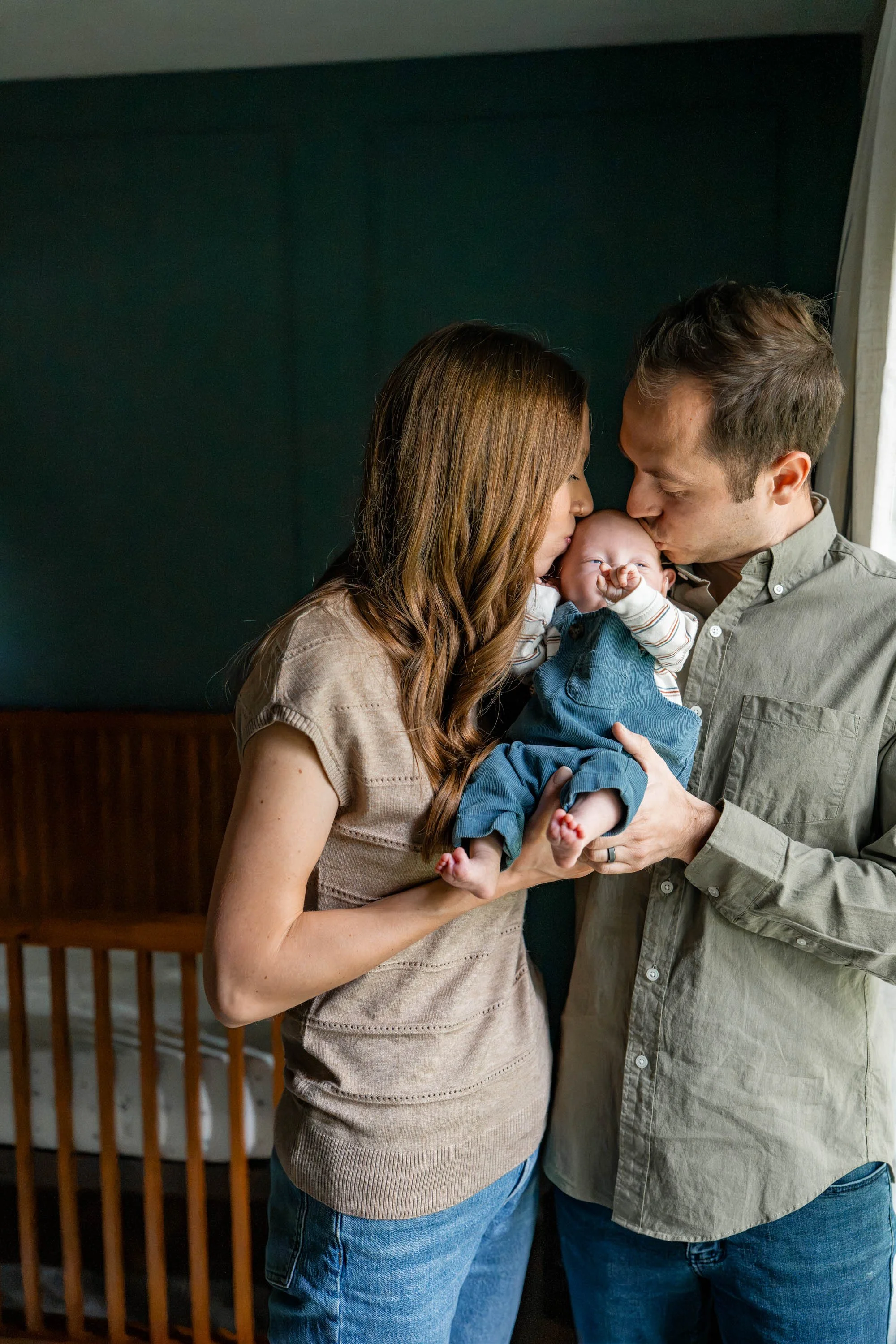 Beavercreek Ohio mom and dad kiss baby boy in his nursery