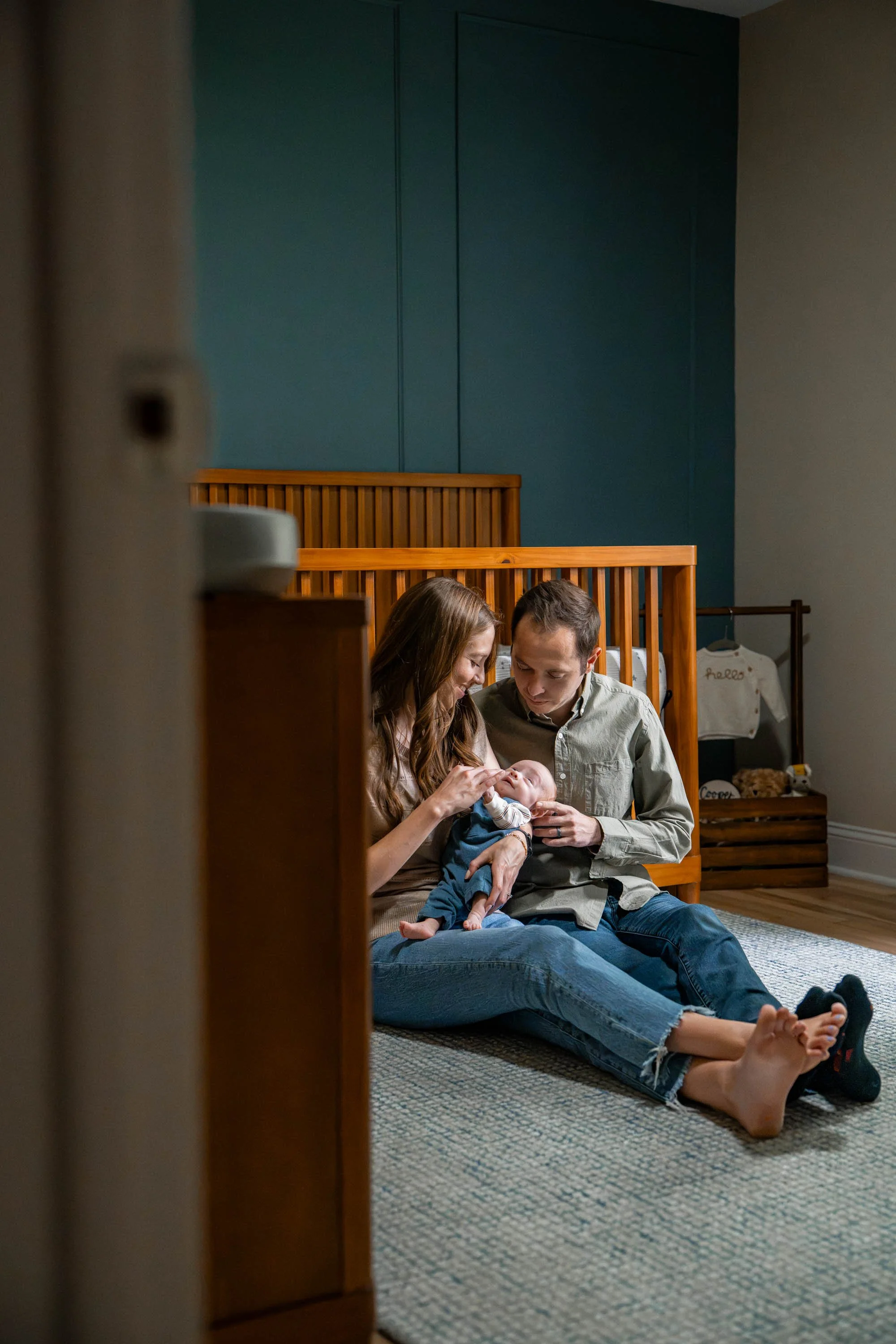 Mom and dad snuggling their newborn in the nursery, Beavercreek Ohio`