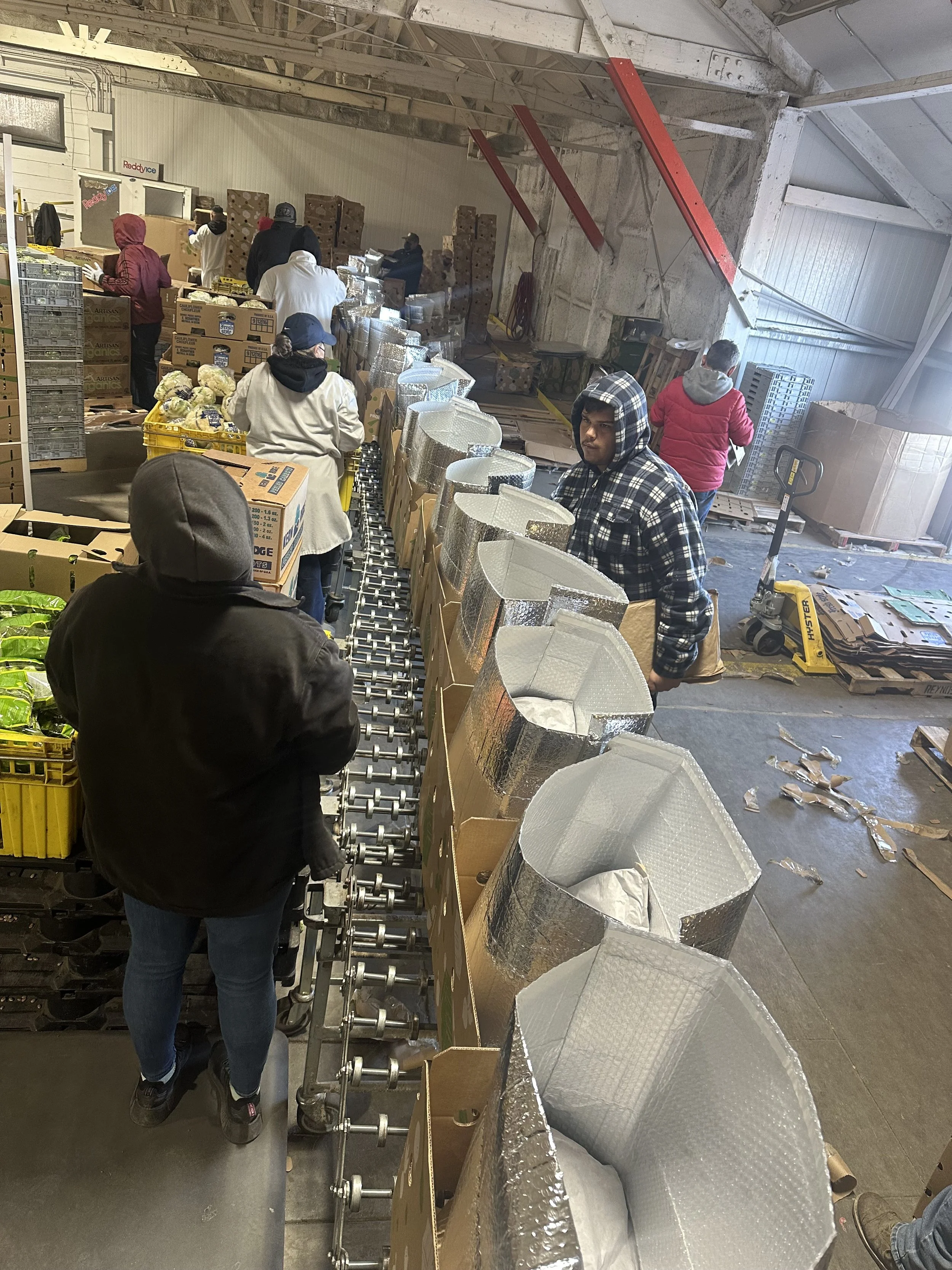 People working in a warehouse or storage area, stacking and organizing boxes and packages.