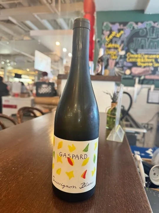 A bottle of Gaspard Sauvignon Blanc wine on a wooden table at a restaurant or cafe.