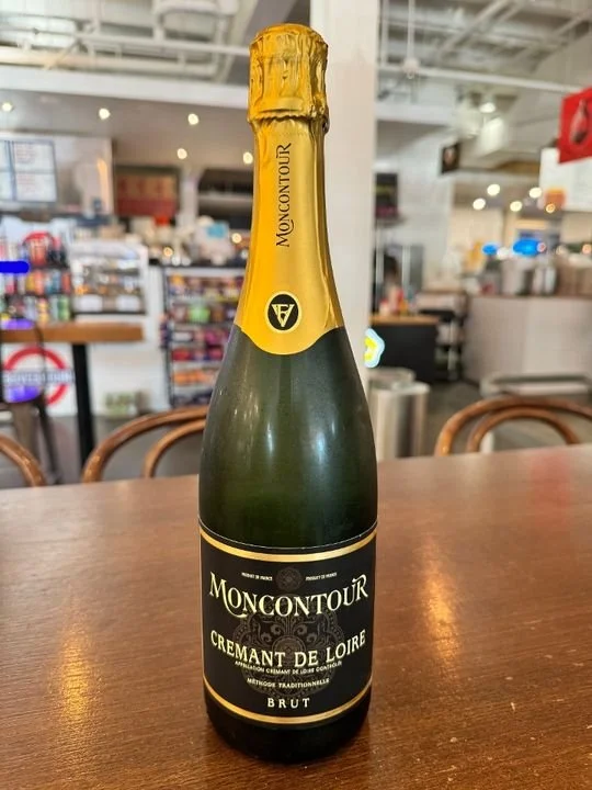 A bottle of Moncontour Cremant de Loire sparkling wine on a wooden table in a cafe or restaurant setting.