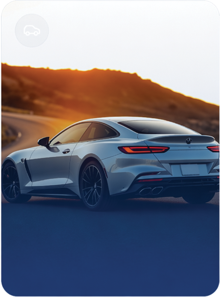 A silver luxury coupe driving on a winding road at sunset, with hills in the background.