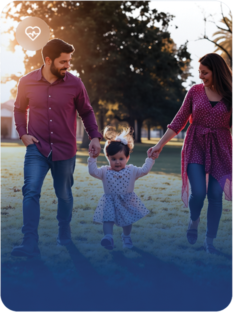 A happy family of three, including a man, woman, and young girl, walking in a park during sunset. The man and woman are holding the girl’s hands as she walks between them, smiling and enjoying the outdoors.
