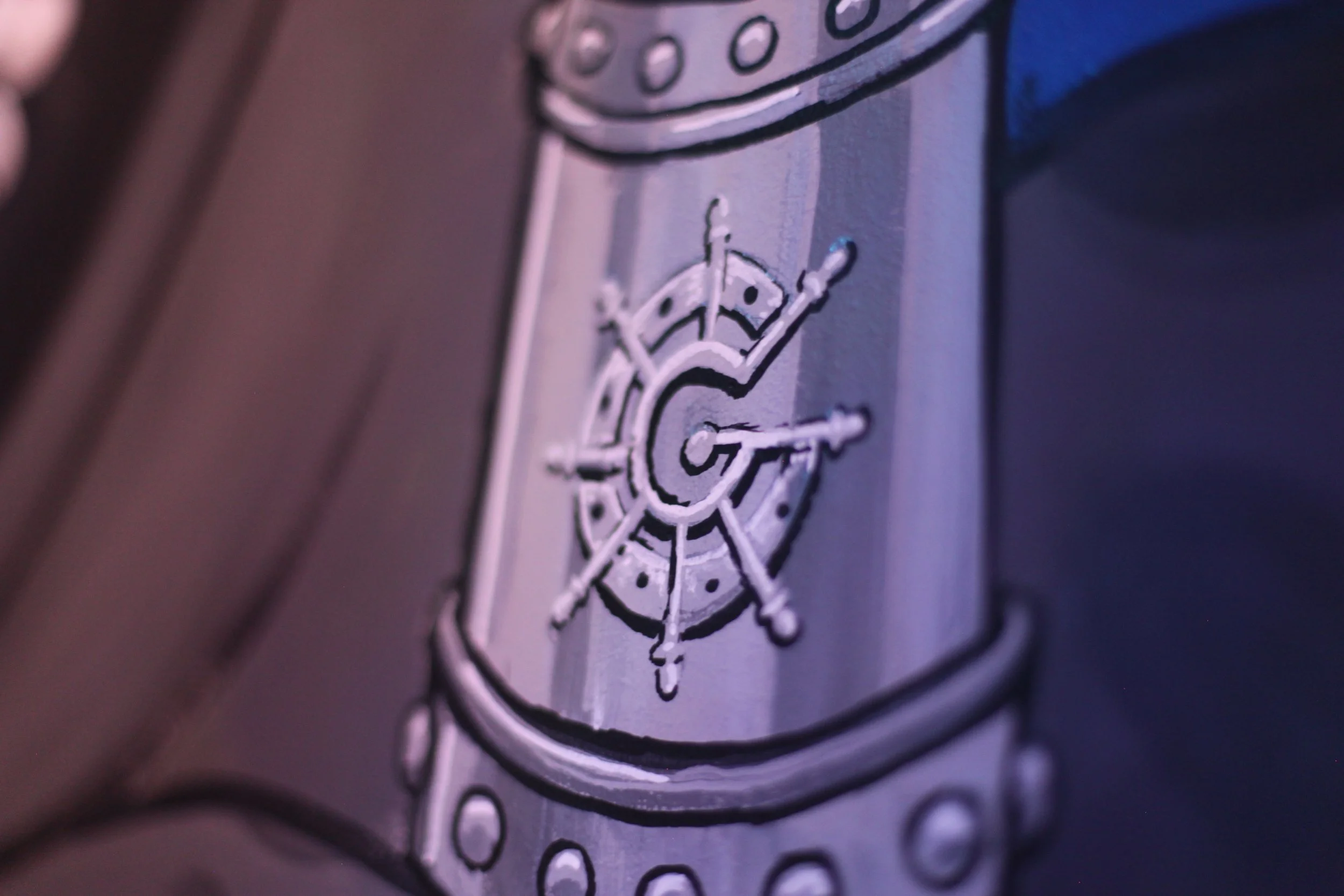 Close-up of a metallic surface with a white outline of a ship's helm and a compass rose, with a large letter 'G' in the center.