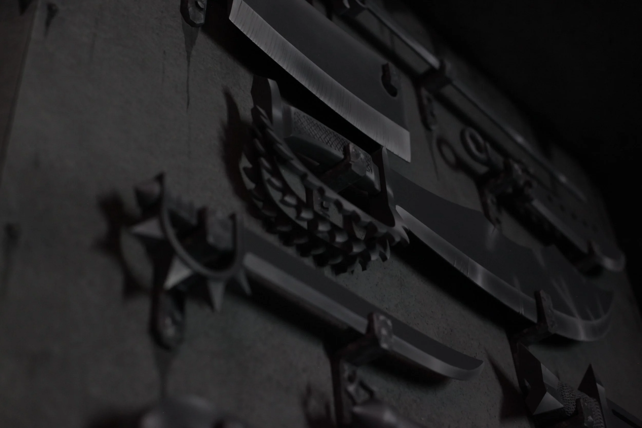 Dark, close-up photo of metallic metal cutout letters and symbols on a concrete surface, partially illuminated, with some shadows inside of Atlas9.