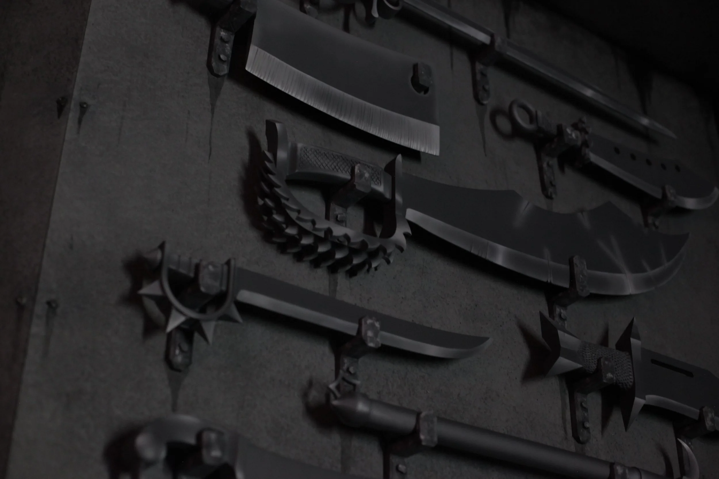 A wall decorated with various metallic weapons and armor, including swords, daggers, and shield-like objects, all mounted in a dark setting.
