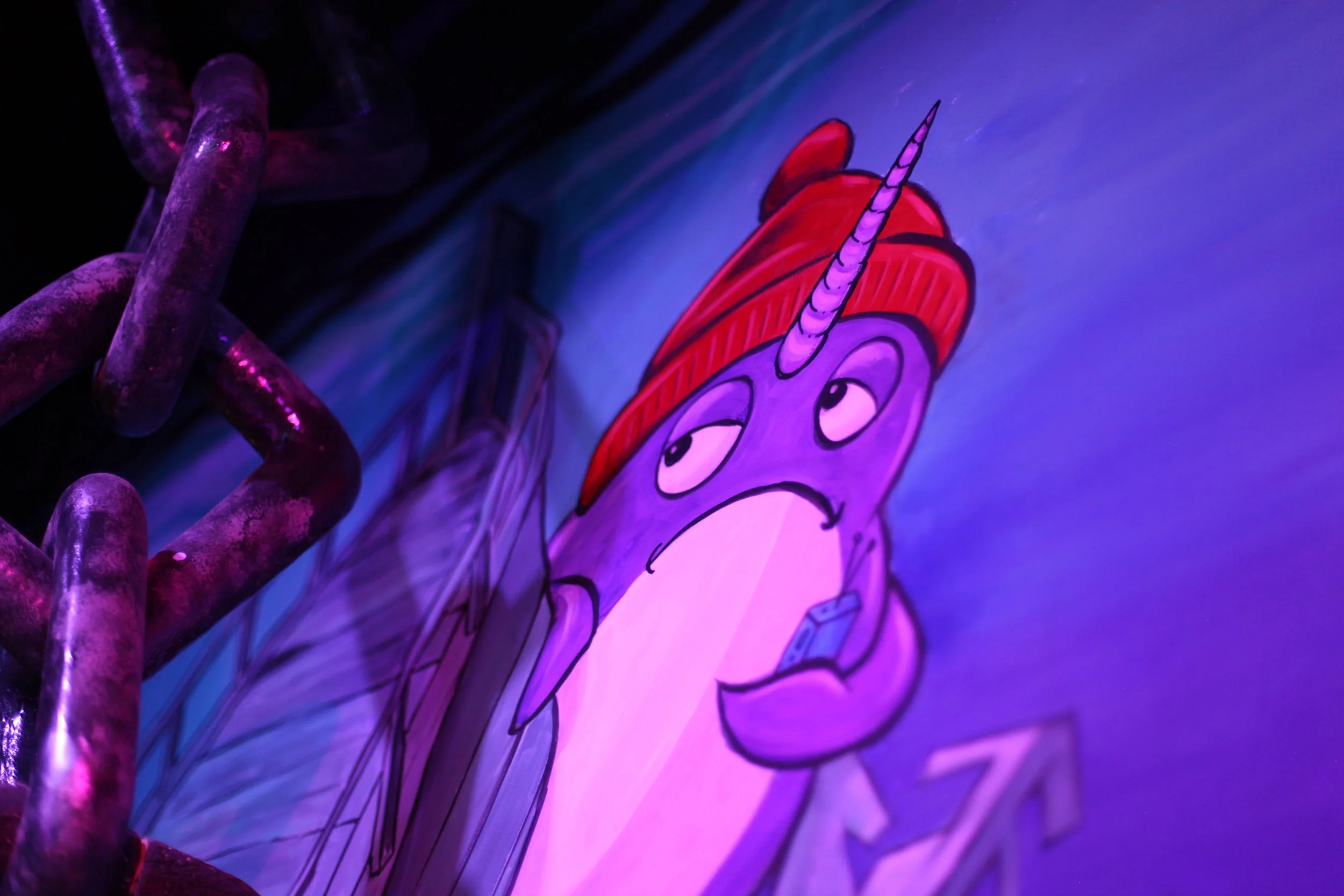 Colorful illustration of a whale with a red hat and a concerned expression, holding a smartphone, under blacklight.