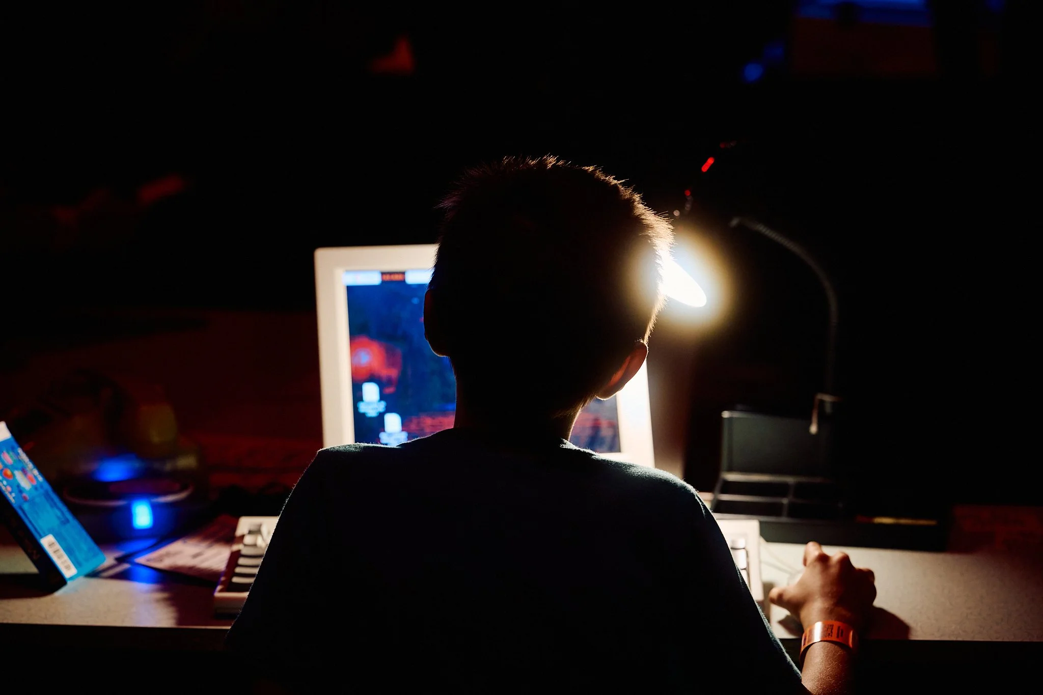 Child investigating mysteries at a computer desk with desk lamp in dark room