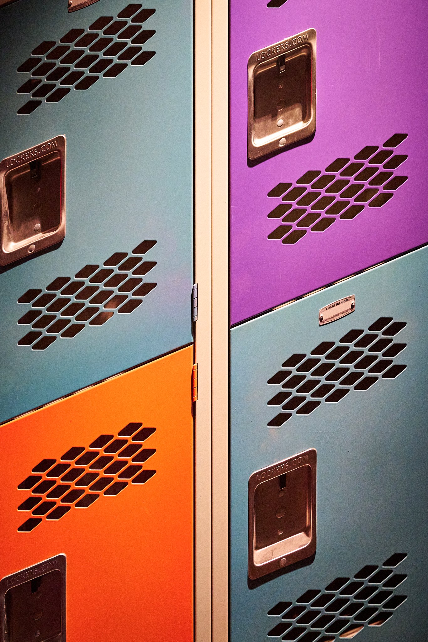 Colorful school lockers with ventilation holes. The lockers are in blue, purple, and orange.