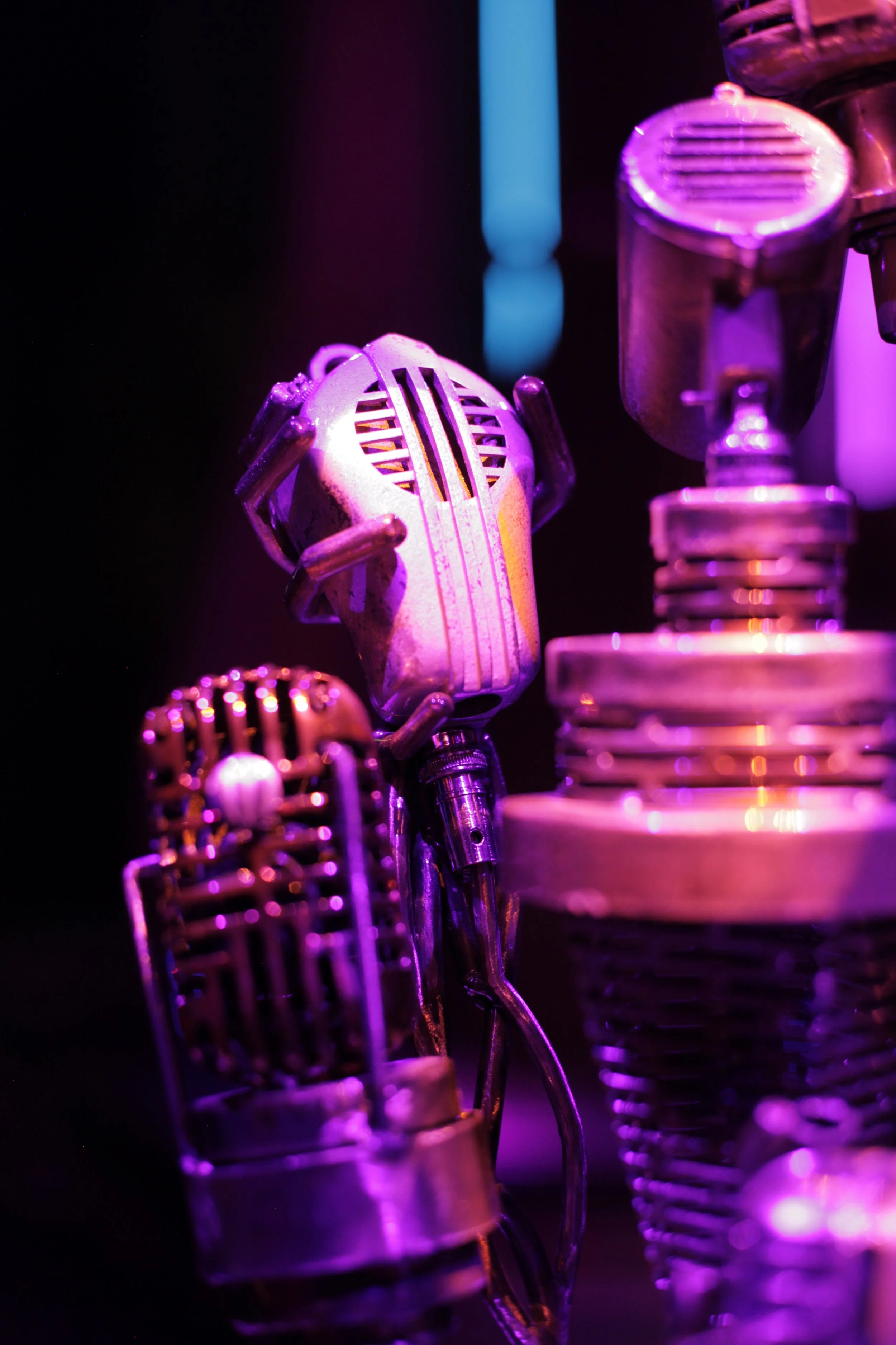 Close-up of vintage microphones stacked and arranged with purple and pink stage lighting in the Jazz club of Atlas9