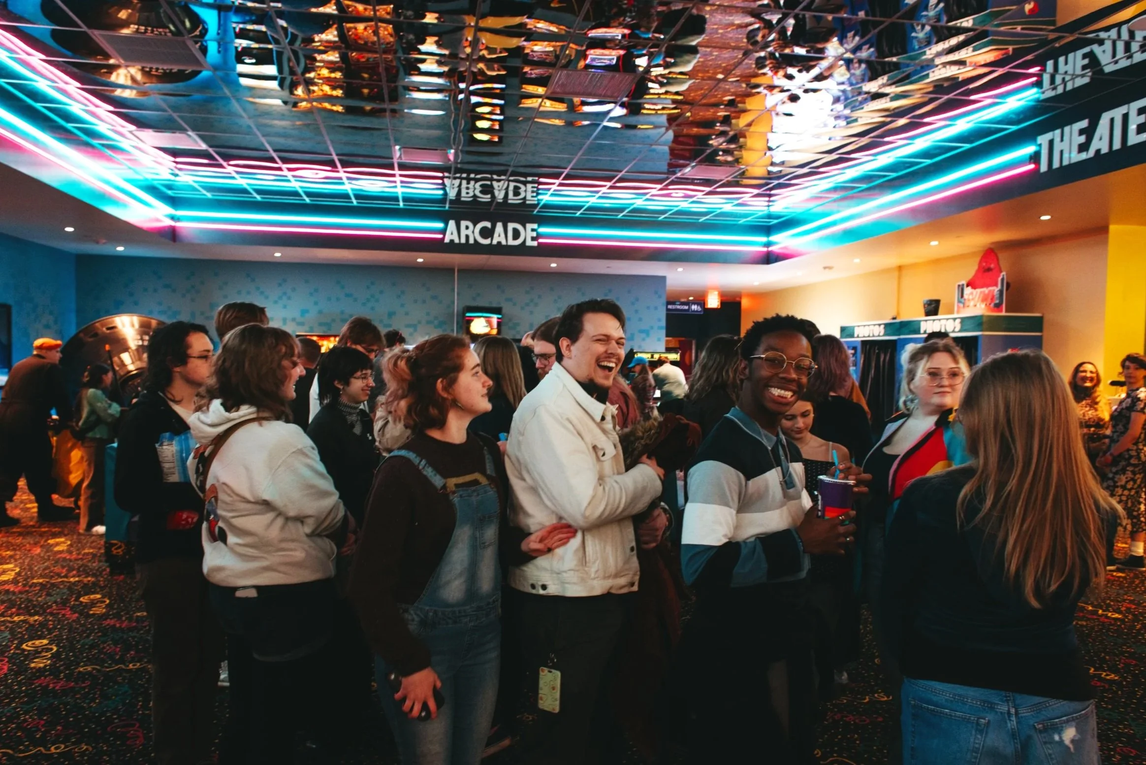 People standing in a line inside Atlas9 happy and excited with colorful neon lights overhead.