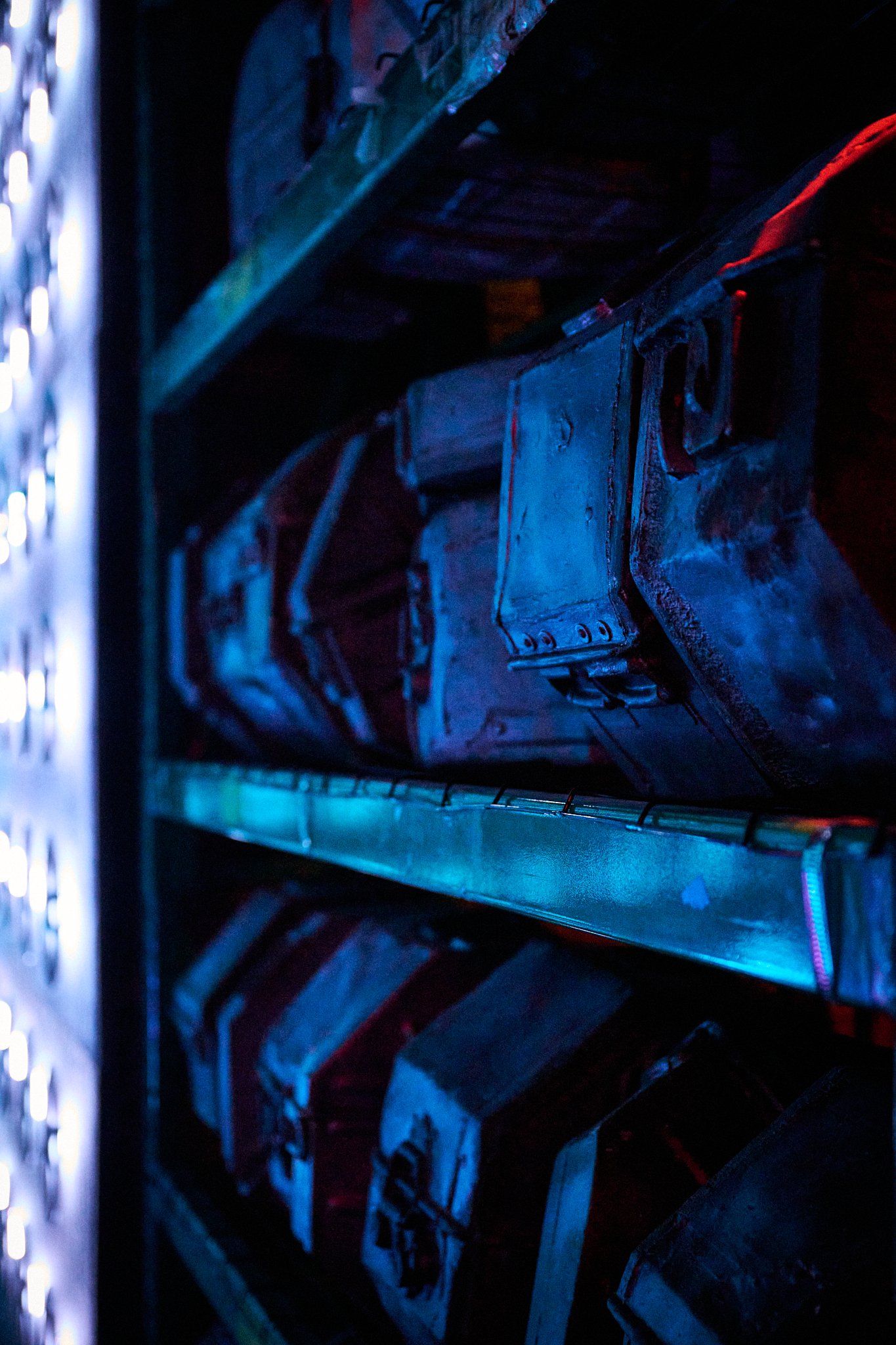 Metal boxes stored on shelves with blue and red lighting.