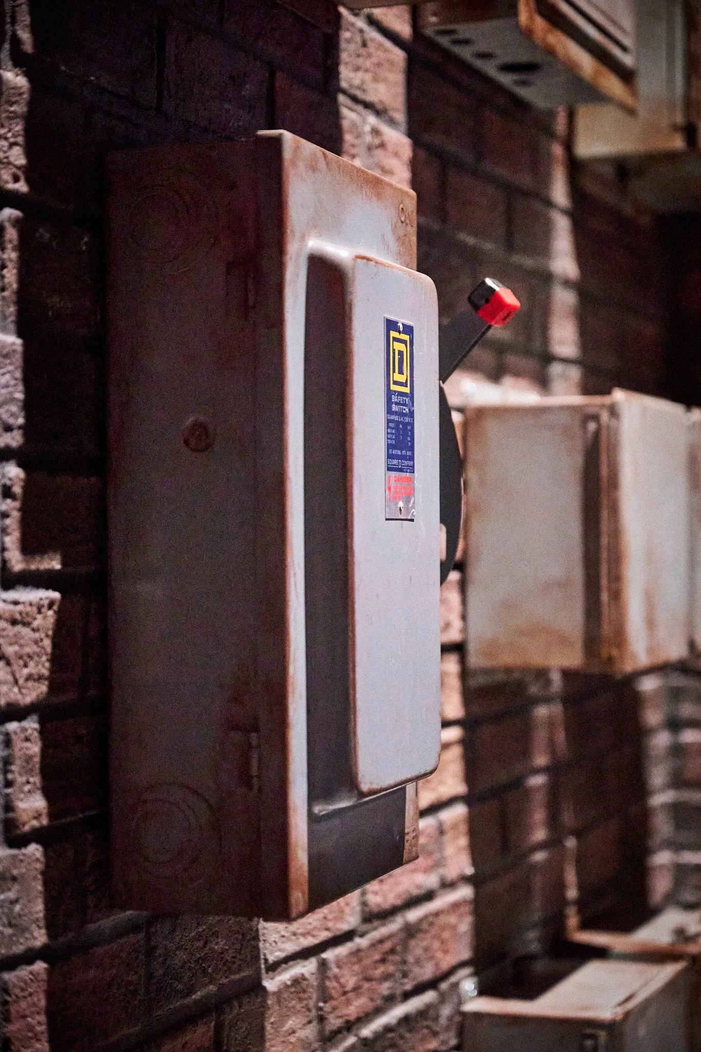 An old electrical safety switch box mounted on a brick wall.