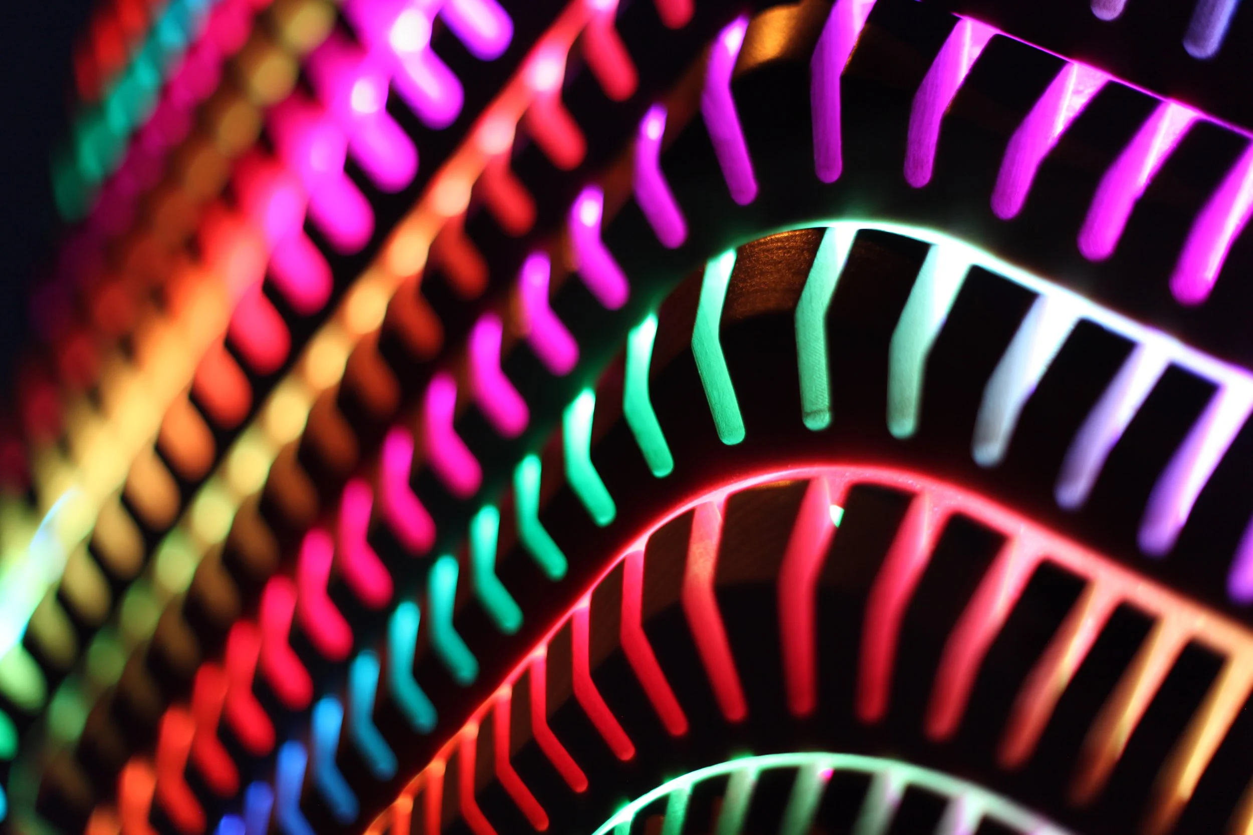 Close-up of colorful LED lights arranged in curved patterns, glowing in shades of red, green, blue, and purple against a dark background.