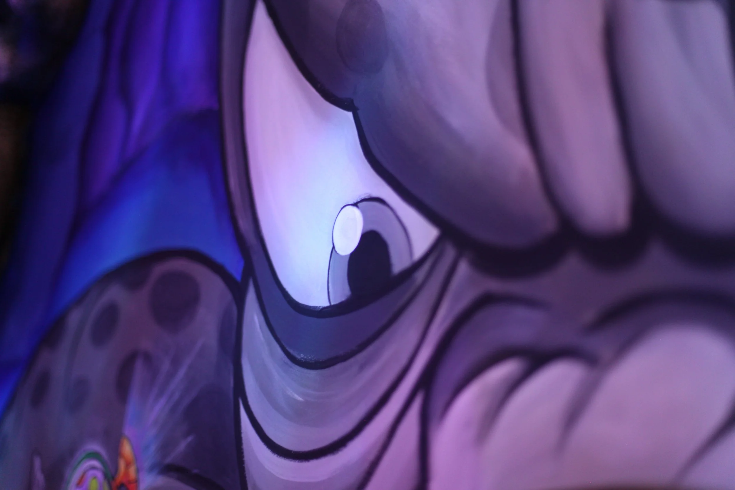 Close-up of a colorful graffiti mural depicting a stylized eye with purple, pink, and blue hues.