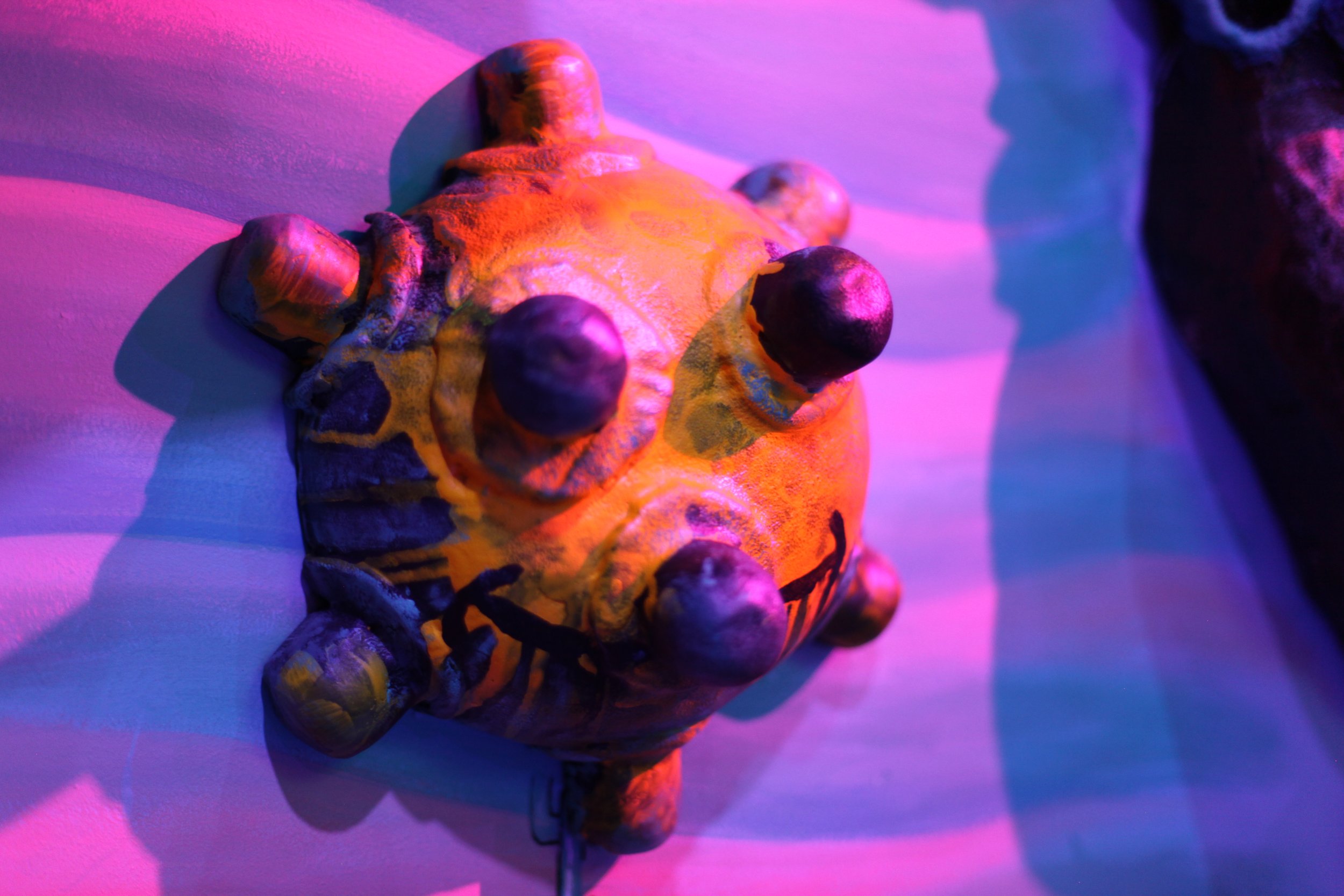 A cartoon sea mine sculpture from an underwater immersive room lit with neon lighting 