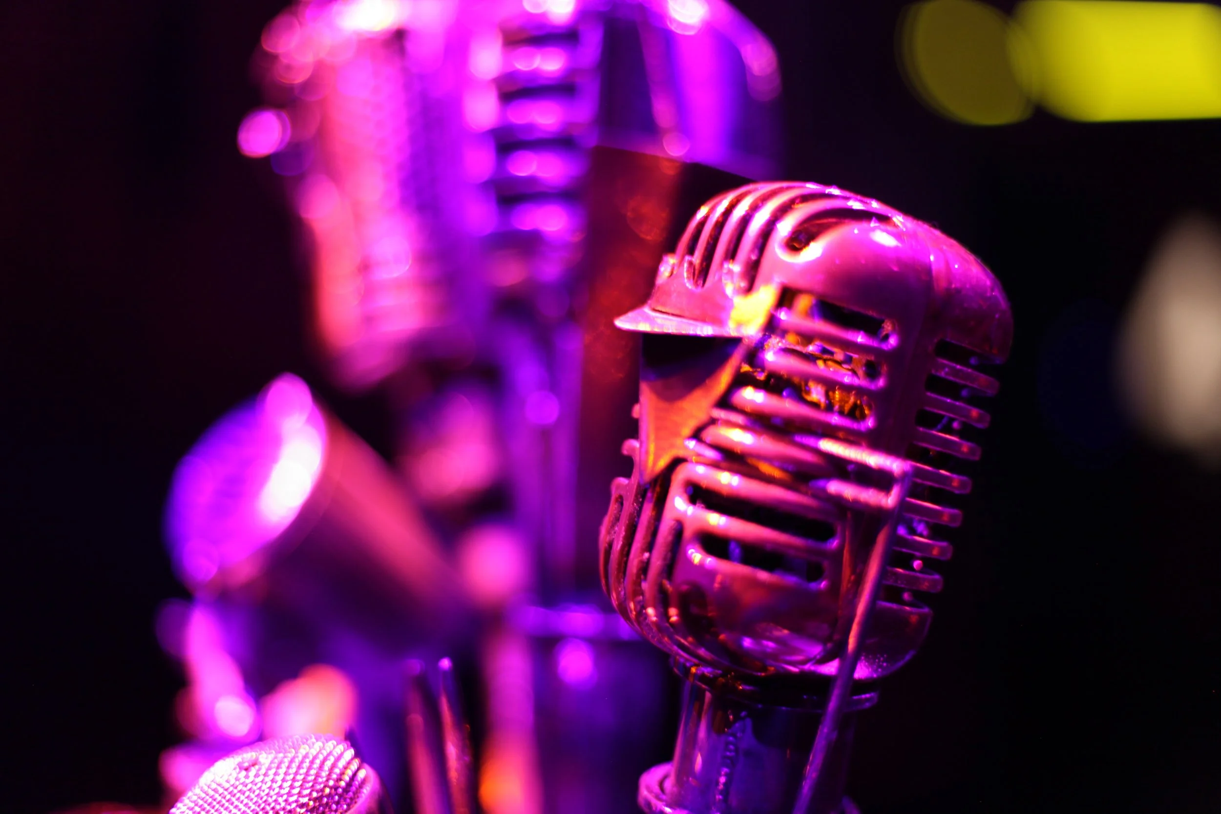 Close-up of a vintage microphone under purple and yellow stage lighting in the Jazz club of Atlas9.