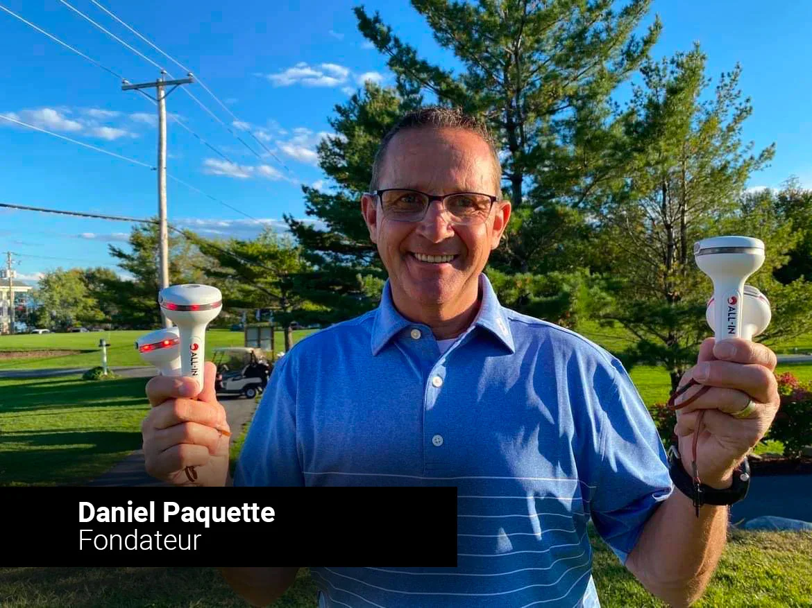 Homme souriant portant des dispositifs électroniques dans un parc en plein jour.