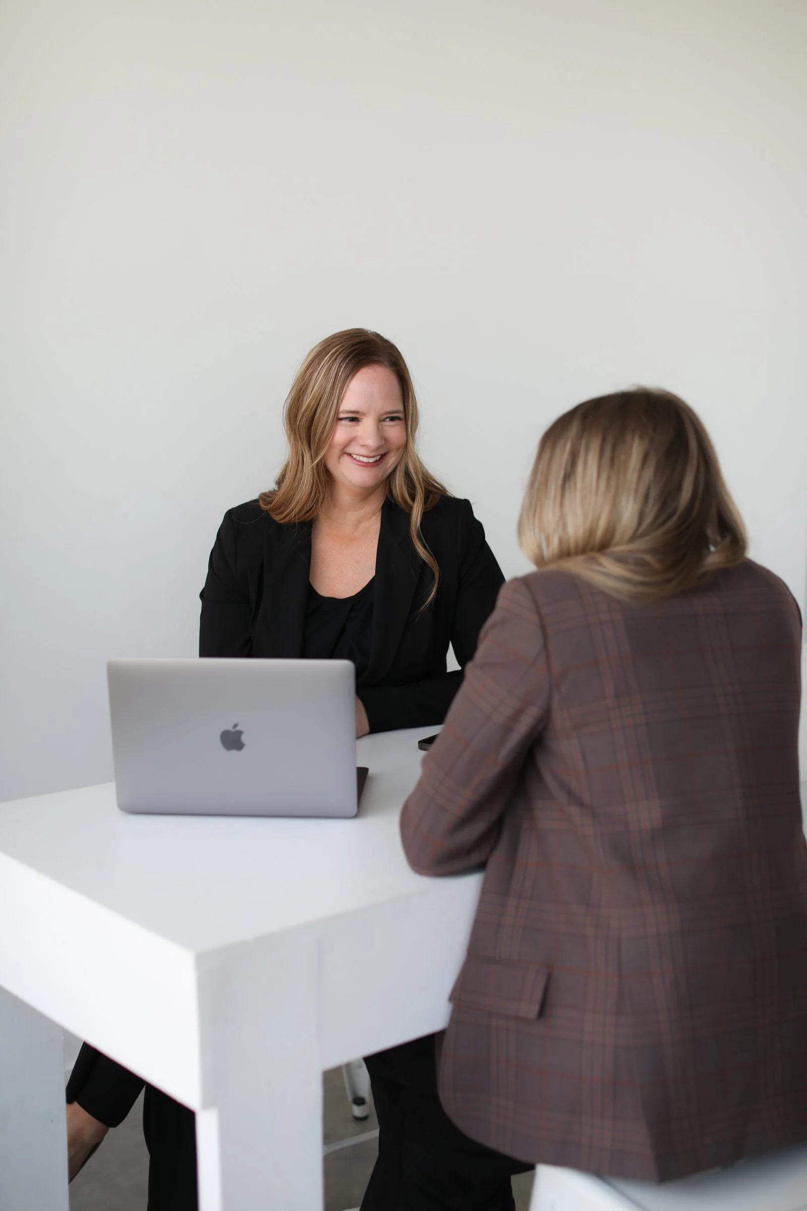 Two women working together at a desk, smiling