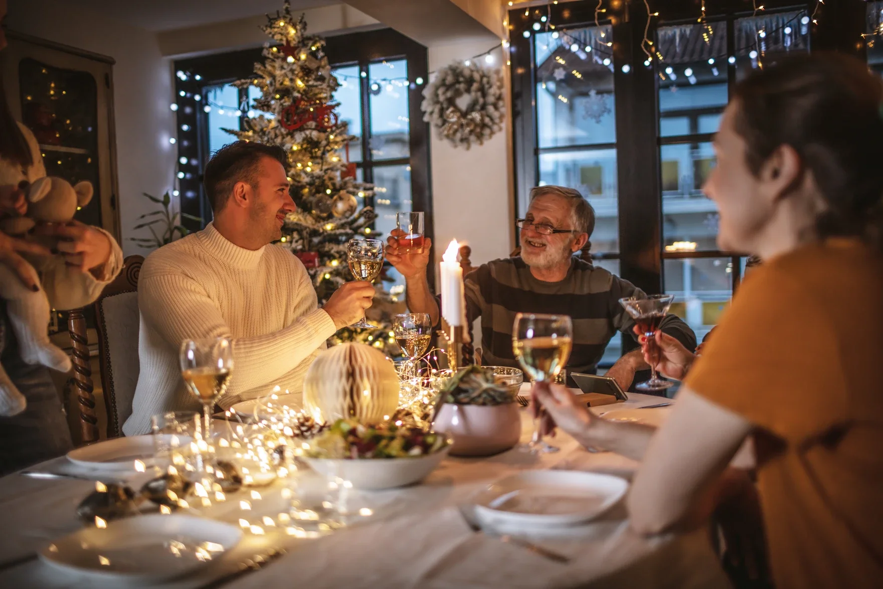 Multiple family members at a festive dining room table celebrating the holidays