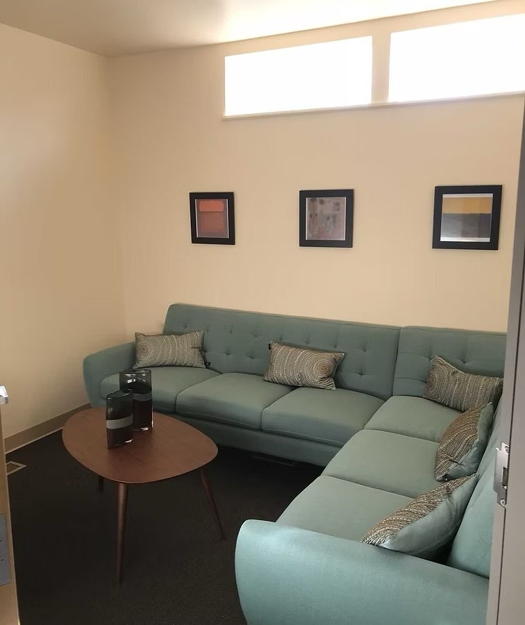 A living room with a sectional sofa, a wooden coffee table, three decorative vases, and three framed pictures on the wall.