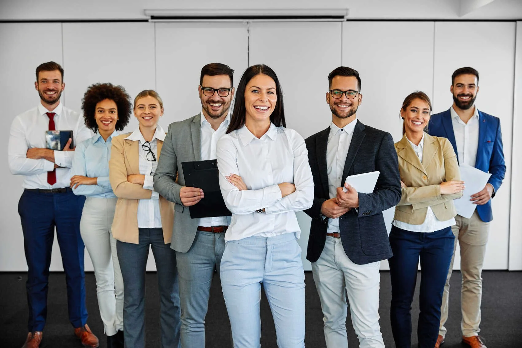 Group of businessmen and businesswomen standing in a conference room posing for a photo