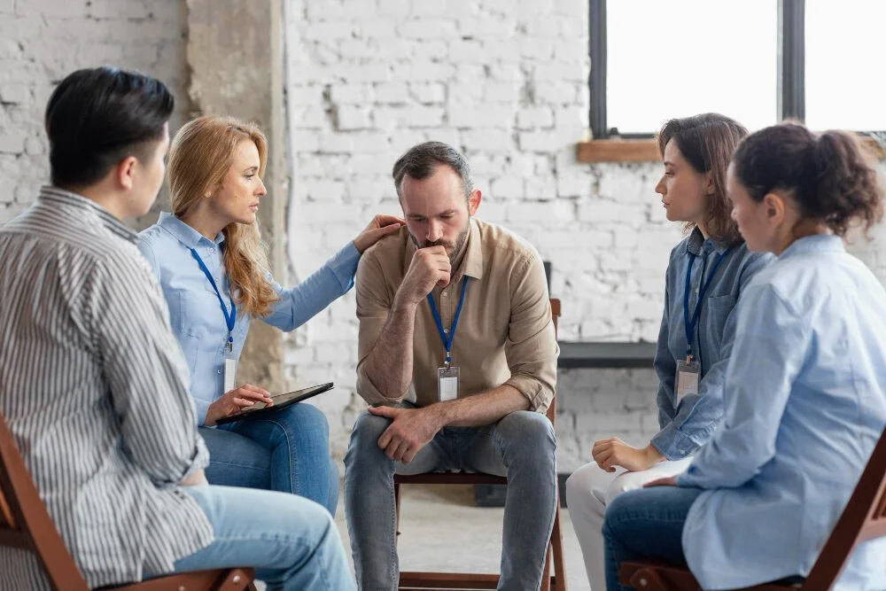 Professional man sitting in group therapy looking sad