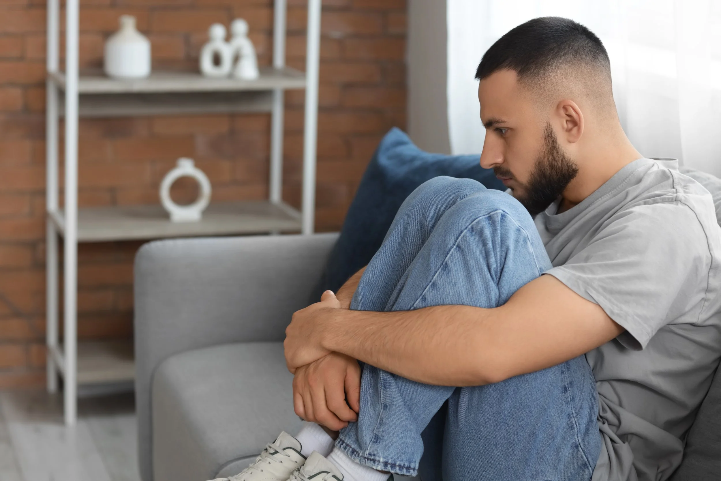 Grief stricken man sitting on a couch by himself