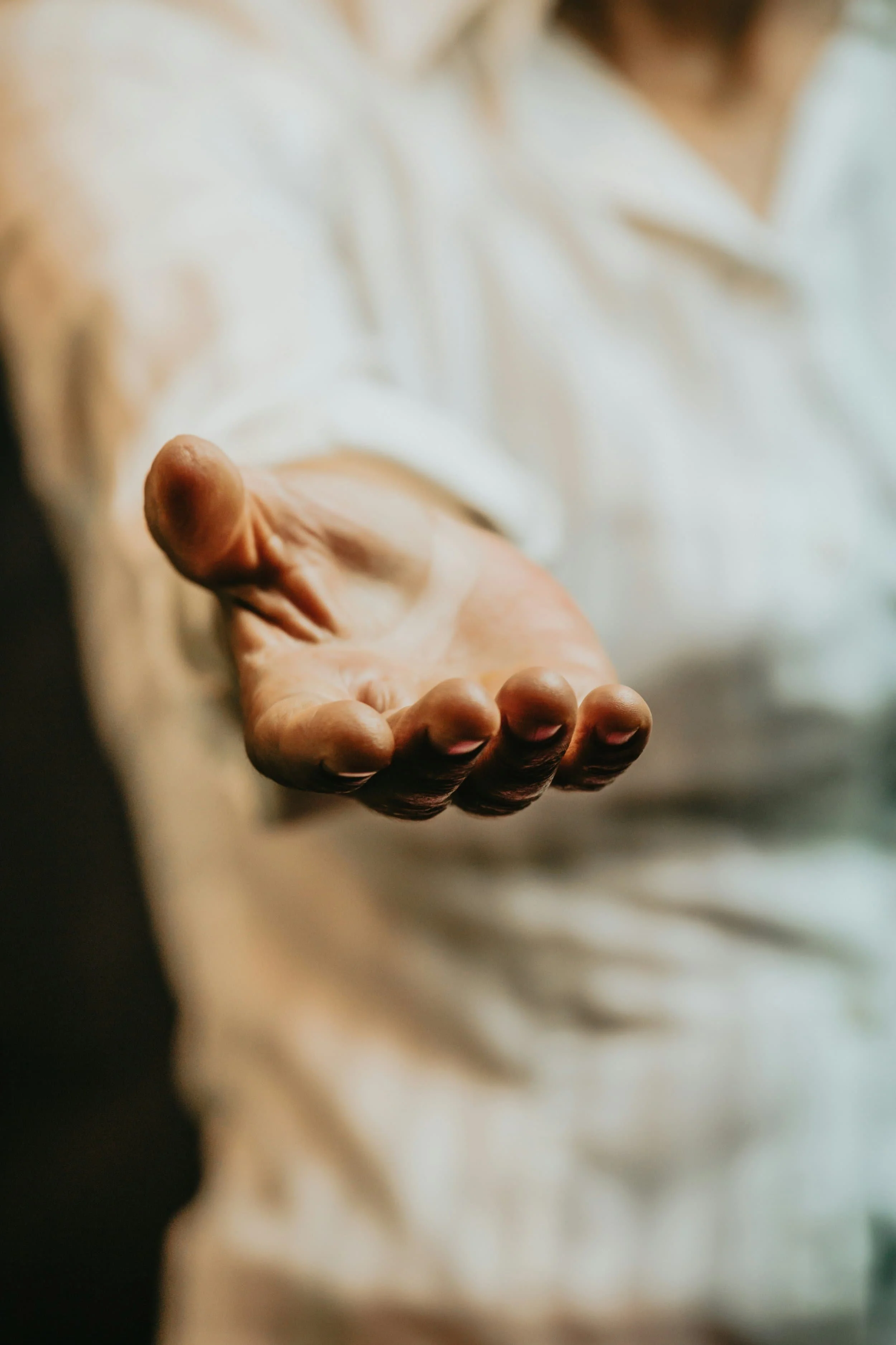 A hand extended outward towards the camera, with fingers slightly curved, in a gesture of offering or reaching out.