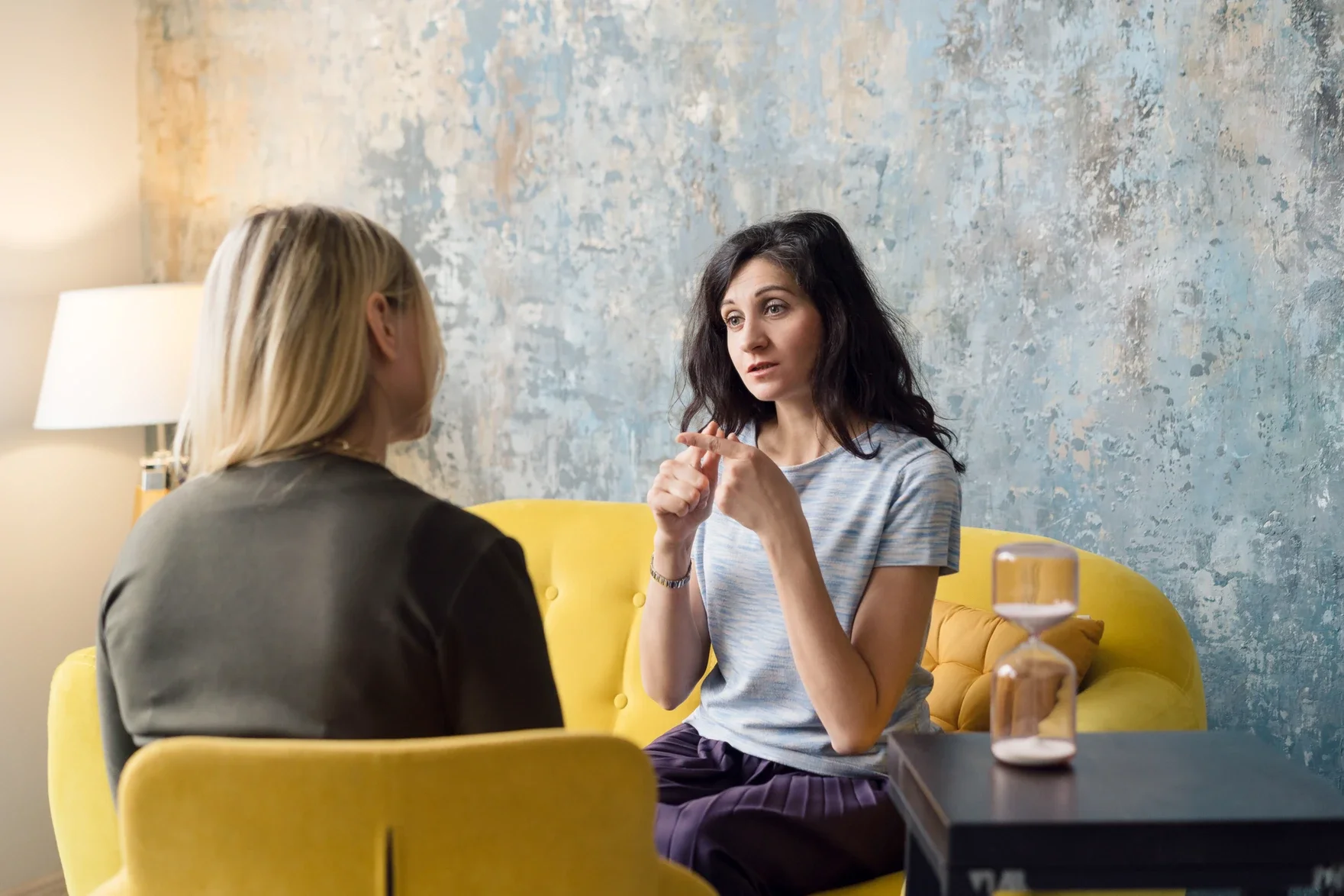 Female client talking to female therapist in a cozy room with yellow furniture