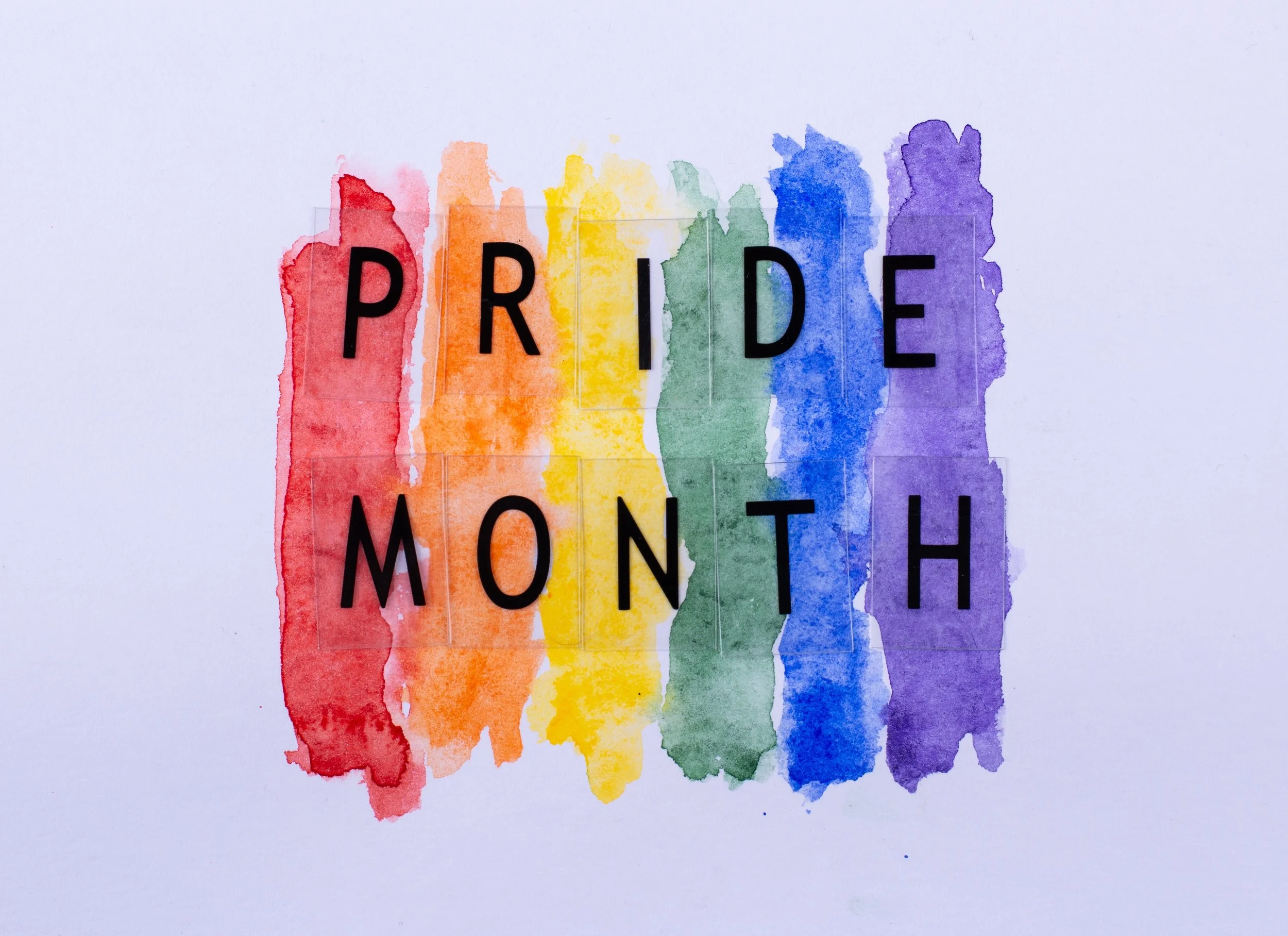 Image of rainbow colors behind "Pride Month" on a white background