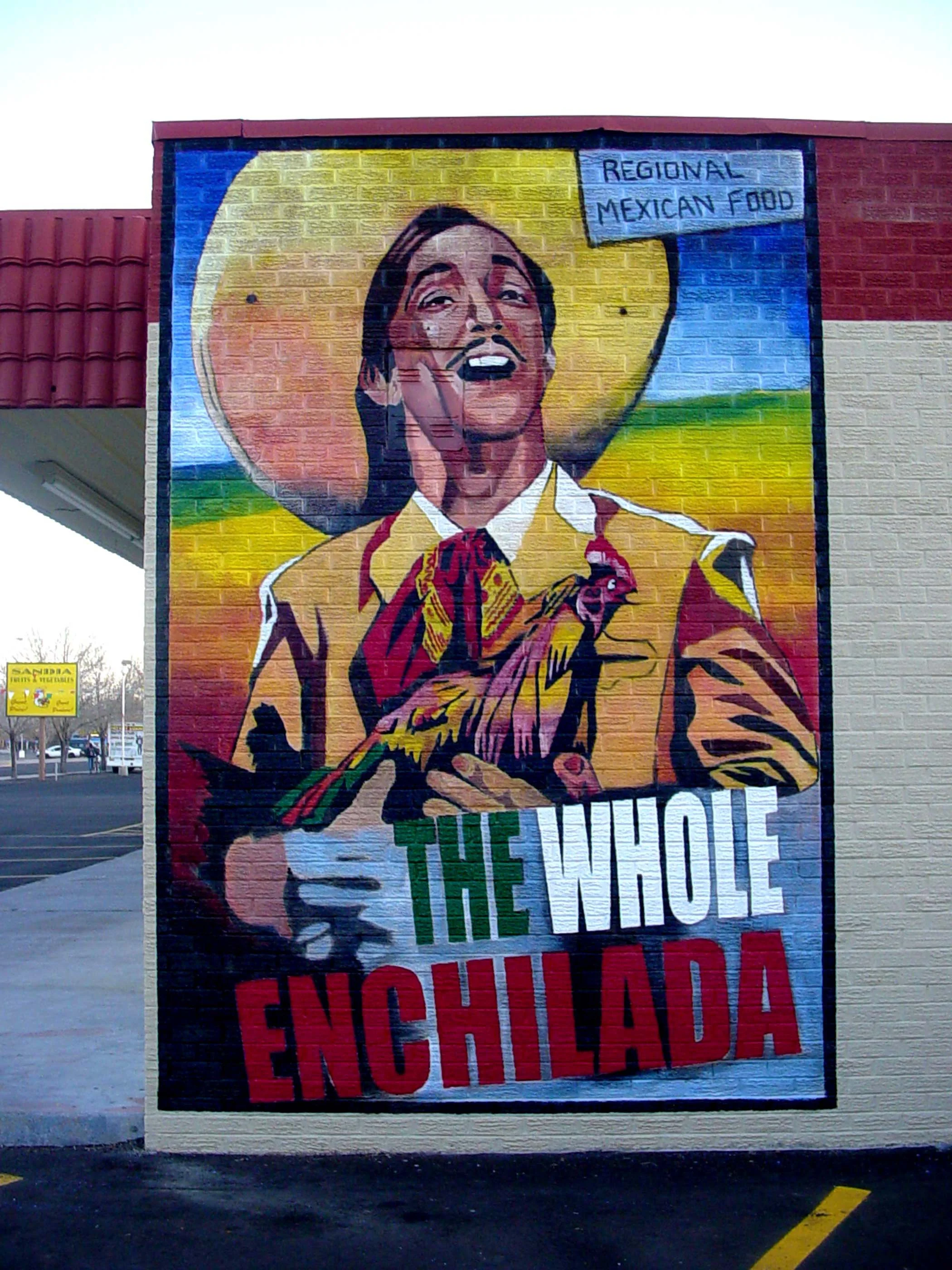 Colorful mural of a man wearing a Mexican sombrero and suit, holding a chicken and smiling. The mural features the text "Regional Mexican Food" in the top right corner and "The Whole Enchilada" at the bottom.