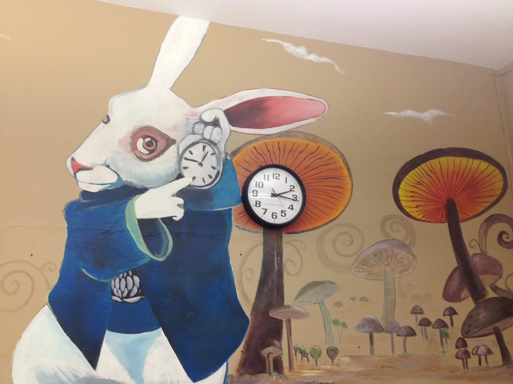 Wall mural of the White Rabbit from Alice in Wonderland holding a clock, surrounded by illustrated large colorful mushrooms, with a clock attached to one of the mushrooms.