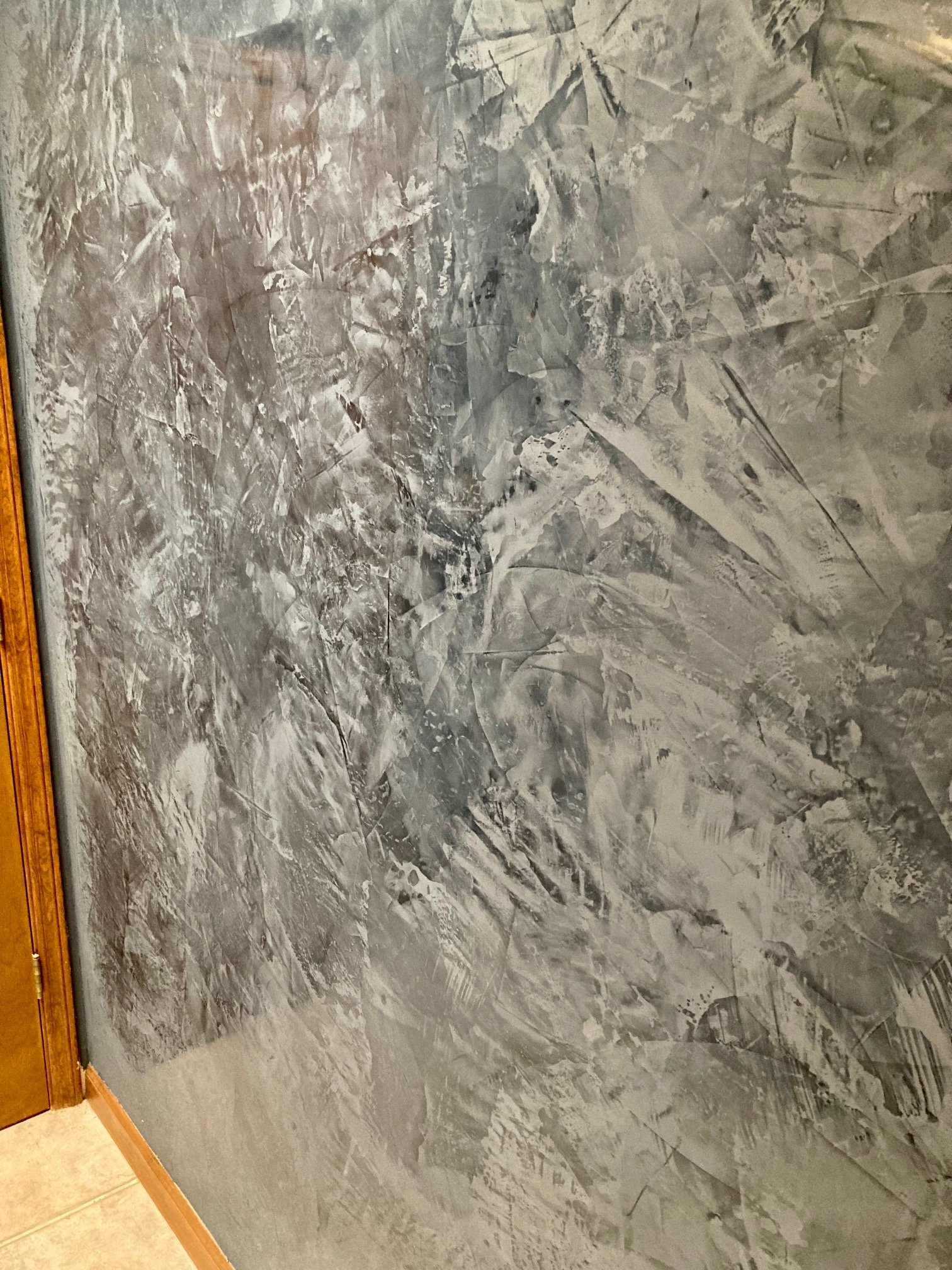 A gray textured wall with a paint or plaster finish, next to a wooden doorframe on the left side.