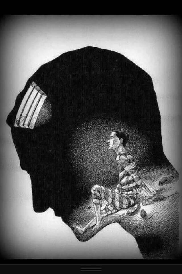 A silhouette of a human head filled with a scene of a person sitting and lying on the ground within a dark background.