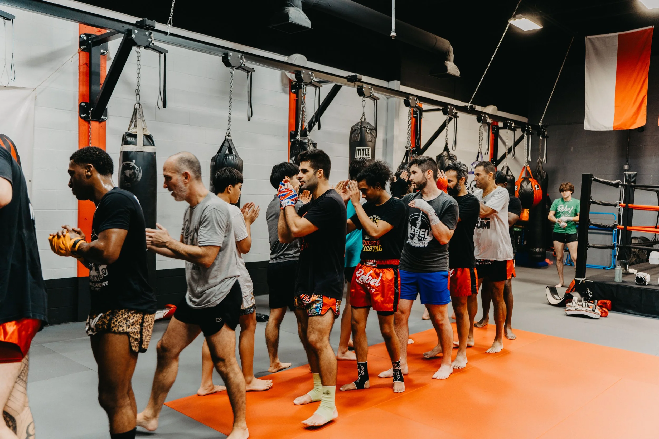 Group of mixed martial arts fighters standing in a line inside a gym, dressed in fight gear, preparing for training or a match.