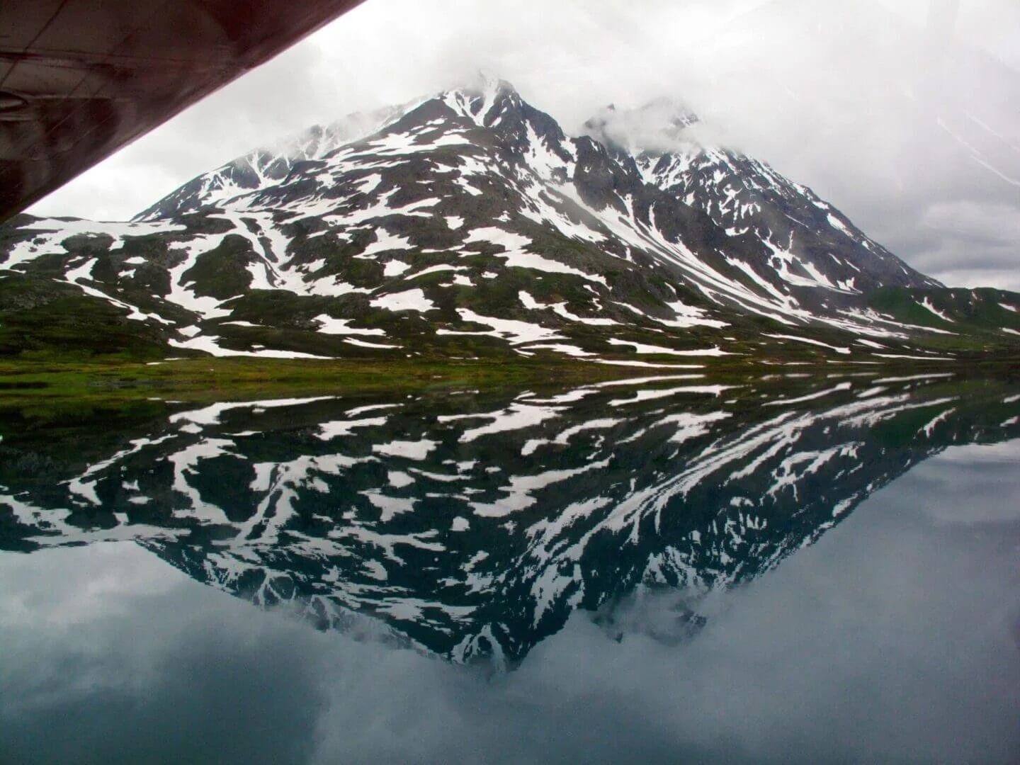 Alaska mountain reflected in calm lake water, scenic view from float plane training at Scout Lake