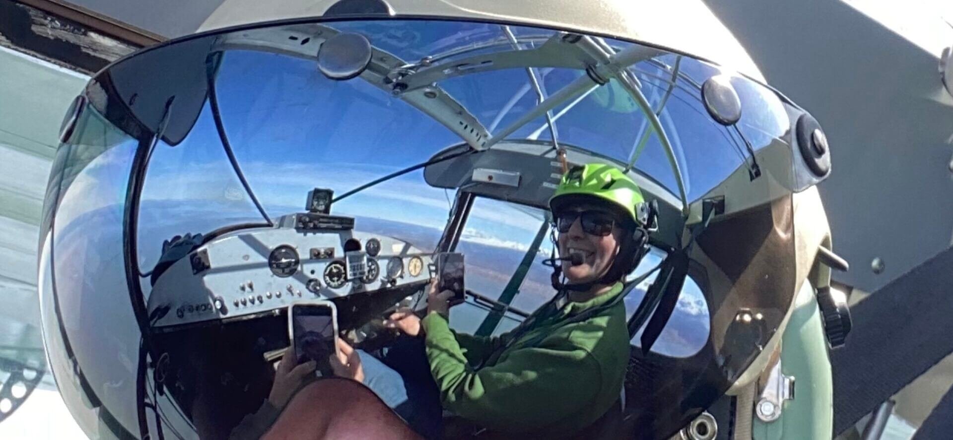 Pilot wearing helmet in cockpit during float plane training flight over Alaska wilderness