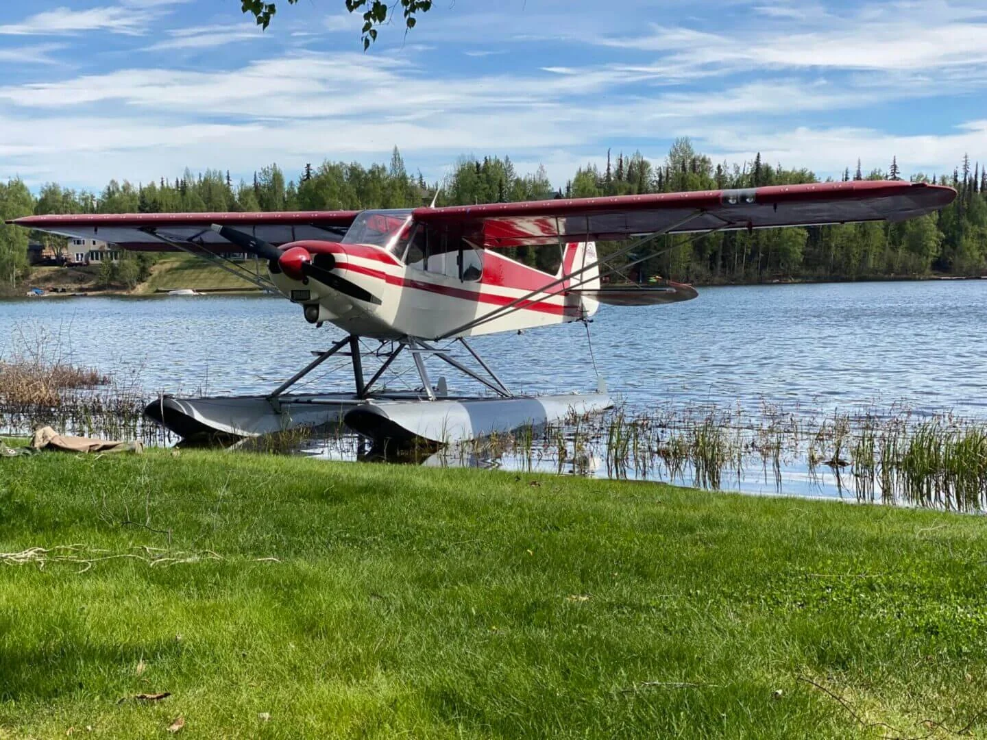 PA-18 Super Cub float plane parked on grass next to Alaska lake at Scout Lake training base