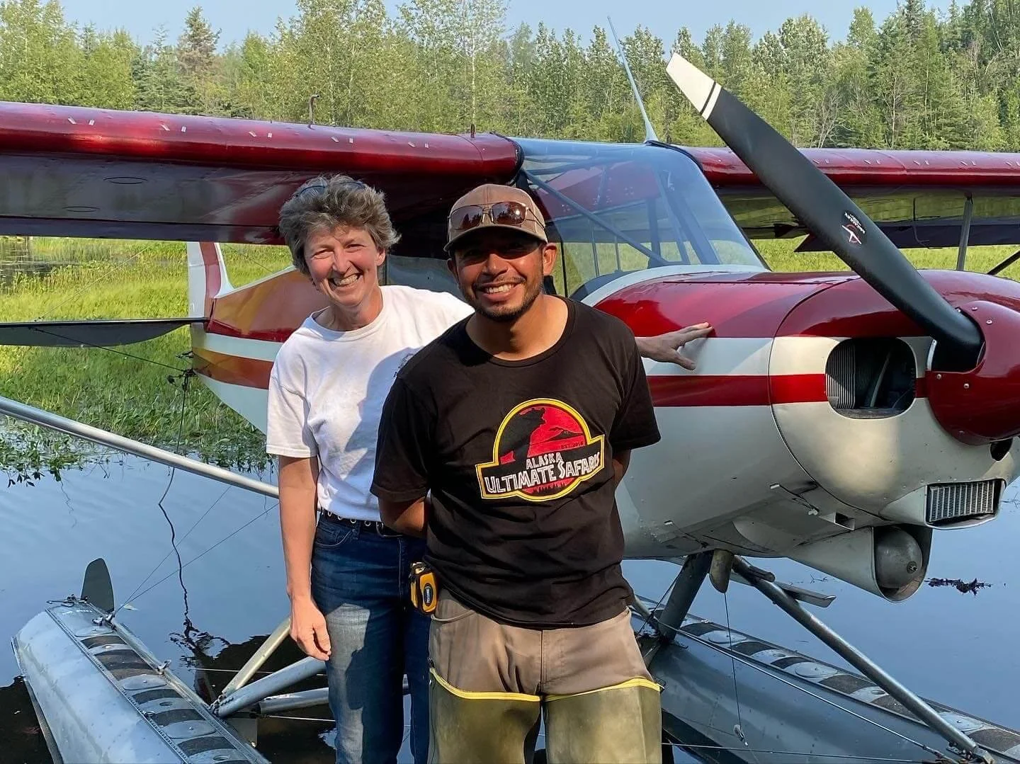 Student and instructor standing next to float plane in water after successful float training Alaska