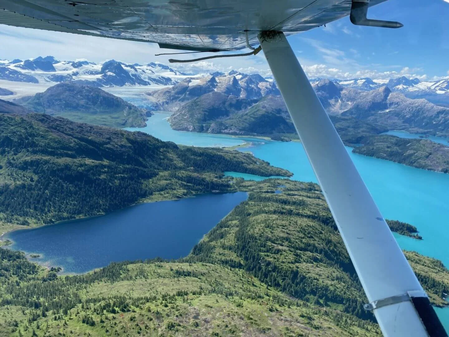 View from wing of float plane over Alaska lake and snow-capped mountains during training flight