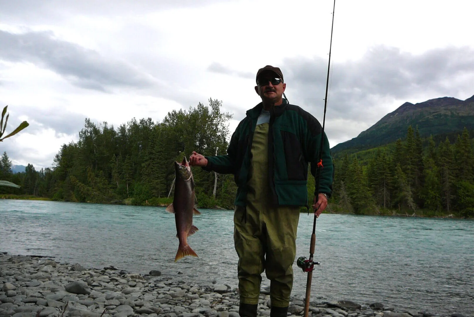 Pilot holding fish on Alaska river, fishing trip accessible by float plane on Kenai Peninsula