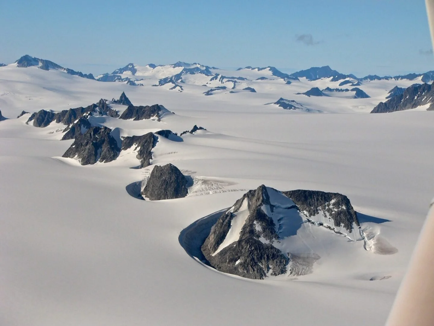 Float plane flying over vast snowfield and mountains during winter training flight in Alaska