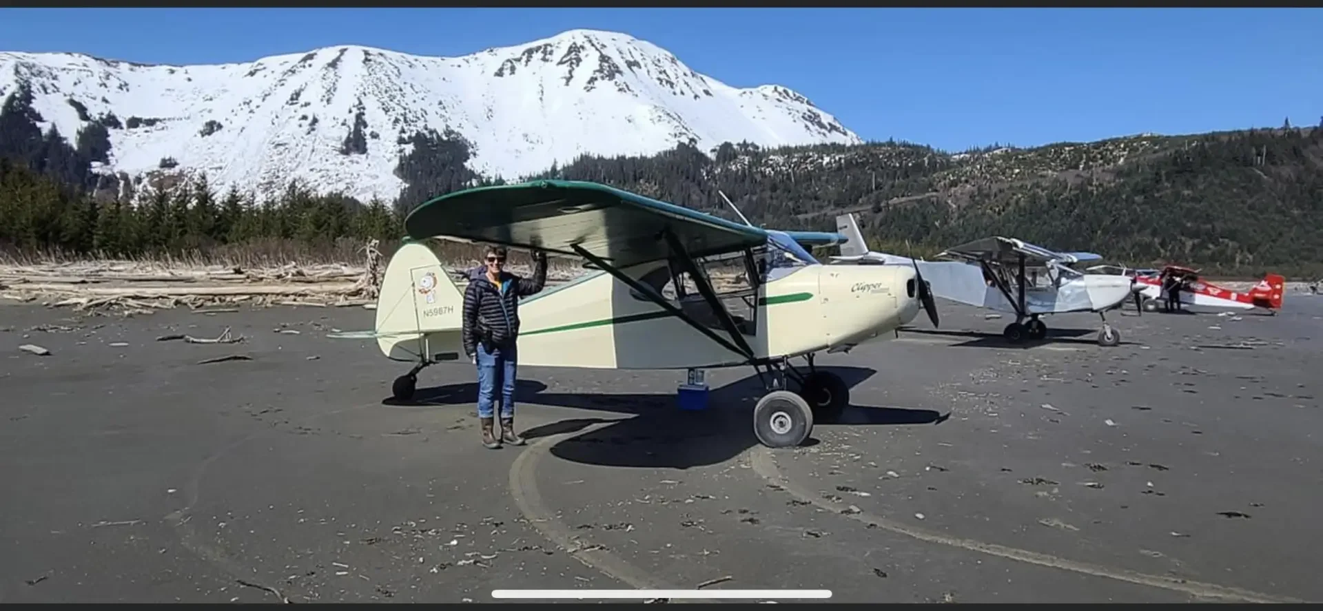 Pilot standing next to classic biplane on Alaska beach, vintage aircraft at Alaska Float Training