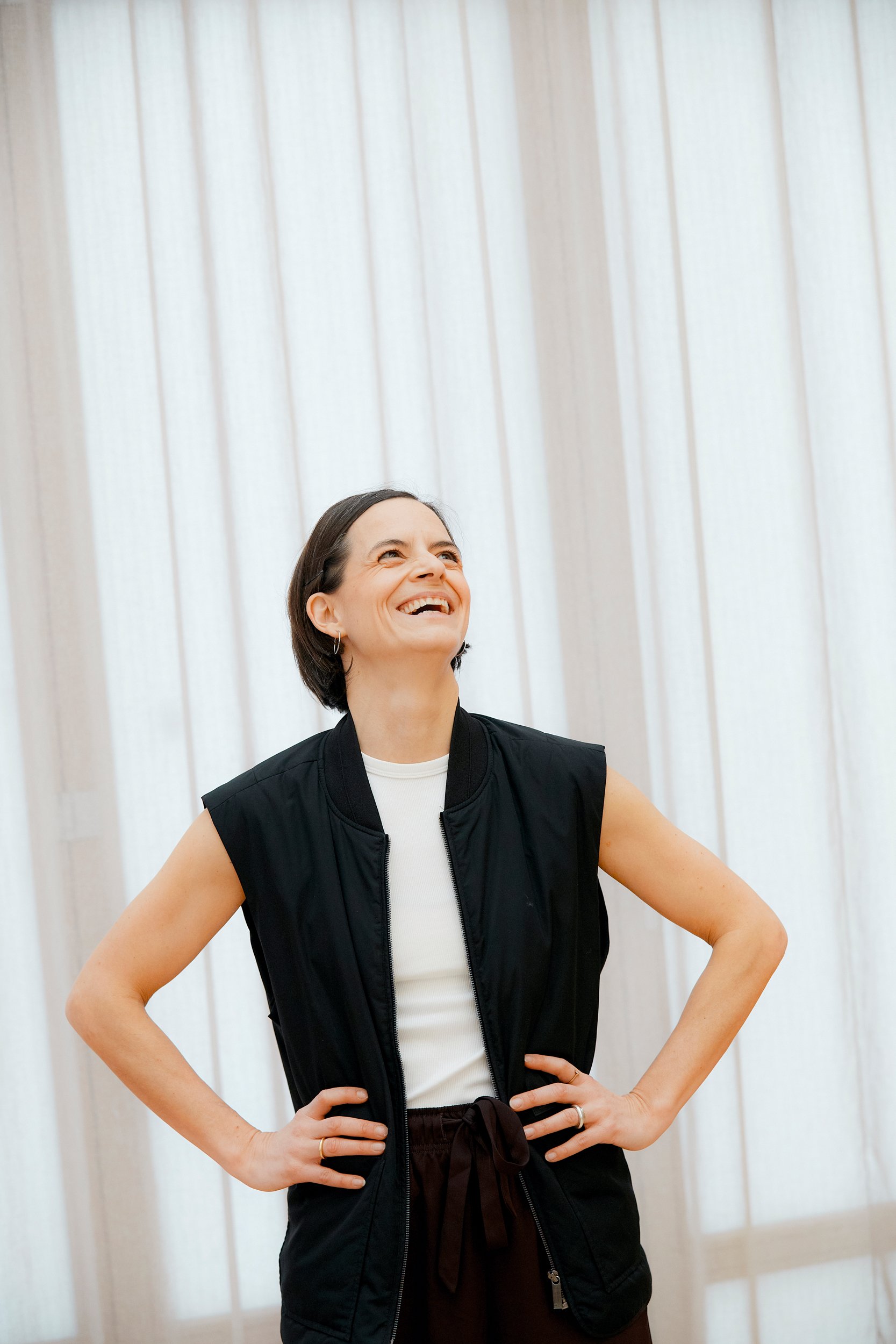 Mitgründerin des Mini Movers Club Berlin lacht herzlich in einem hellen Sportstudio während eines Kurses für Eltern und Kinder.