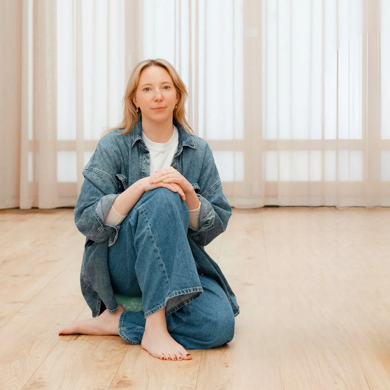 Gründerin des Mini Movers Club Berlin sitzt lächelnd in ihrem hellen Sportstudio für Eltern-Kind-Kurse