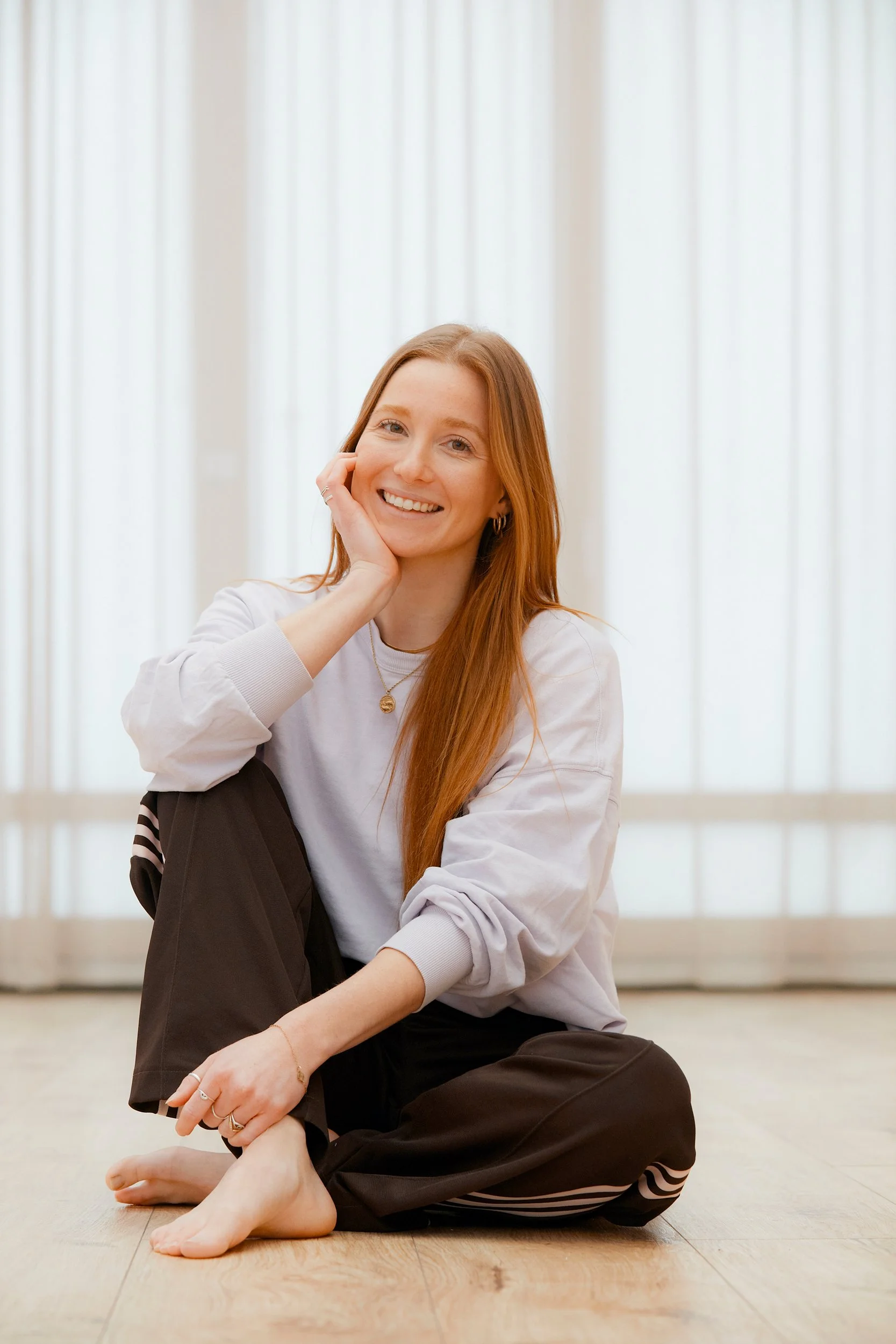 Annabelle Voigtmann, Kids-Trainerin im Mini Movers Club Berlin, sitzt lächelnd auf dem Boden eines hellen Sportstudios für Kinderkurse.