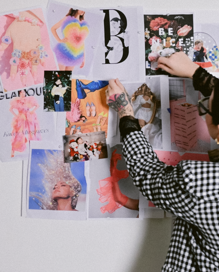 Person pinning a collage of colorful and artistic images on a wall, including butterflies, people in fashion poses, and vibrant artwork.